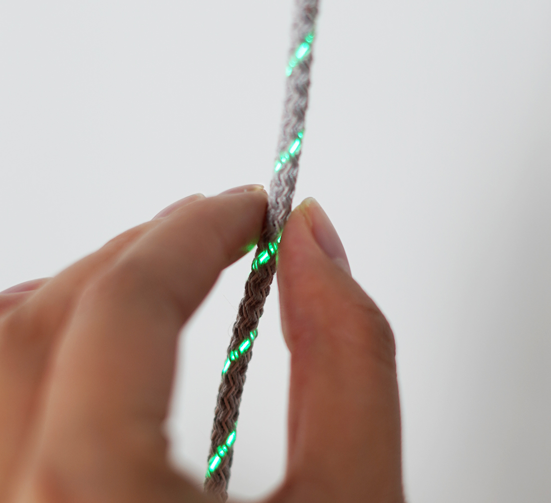 I/O braid in hand with illuminated fiber optic strands